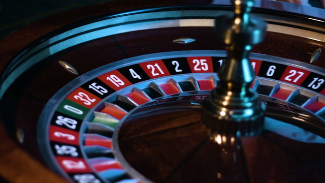Russian roulette wheel is spinning at a casino and the small white ball is lying in a slot.