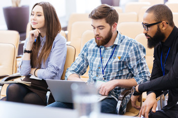 Young business people using laptop sitting on meeting