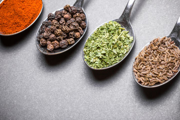 Colorful spices on old metal spoons.