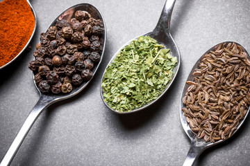 Colorful spices on old metal spoons.