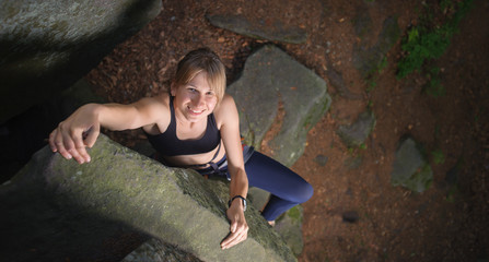 Top view of cute female climber looking up and smiling, rocky ba