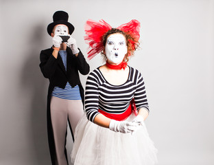Funny couple of mimes taking a selfie photo on a mobile phone. Concept of  April Fools Day.