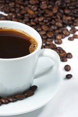 Cup of coffee with coffee beans isolated on white background.