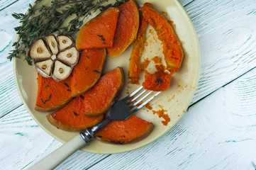 Pieces of baked pumpkin on yellow plate with fork. Vegetarian food.