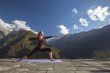 Young girl doing yoga fitness exercise outdoor in beautiful mountains landscape. Morning sunrise,...