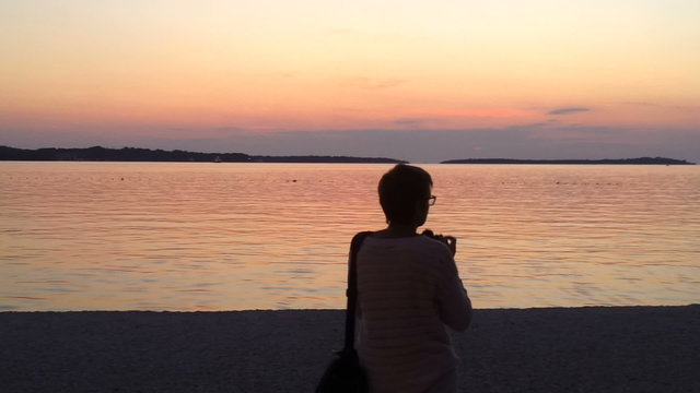 Woman shoots calm see after sunset