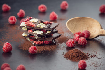 Sweet chocolate slices with fruits, cocoa powder and wooden spoon. sweet dessert on black background. image for patisserie