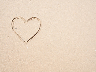 Fototapeta na wymiar Heart-shape drawing on the sandy beach with sea background