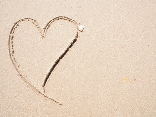Heart-shape drawing on the sandy beach with sea background