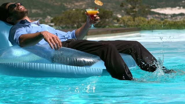 Businessman sitting on buoy while drinking cocktail