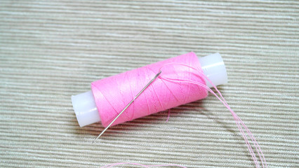 Spool with pink thread with needle