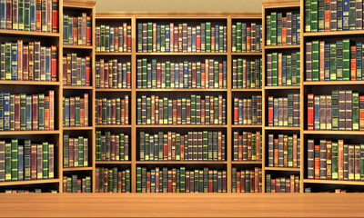 Table on background of bookshelf full of books . Old library.