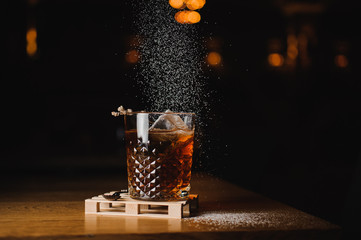 dusting whiskey drink with  ice  on  wood in bar