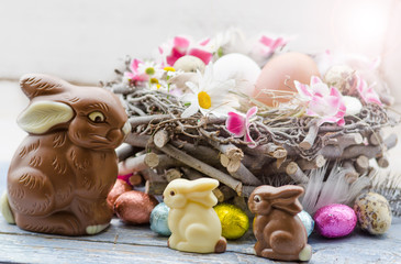 Happy Easter: nest with Easter eggs, feathers, flowers and chocolate bunnies :) - 103014659