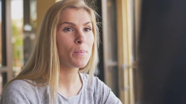 A young woman talking to her friend at a cafe