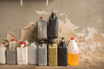 A group of dirty plastic container against a wall, in a workshop.