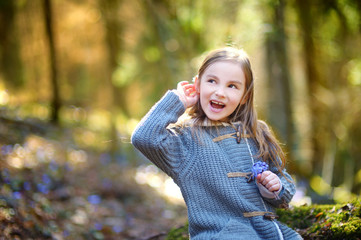 Adorable little girl picking the first flowers of spring in the woods