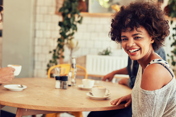 Cheerful young woman at a cafe with friends - Powered by Adobe