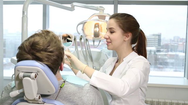 young doctor dentist examines the mouth of the patient