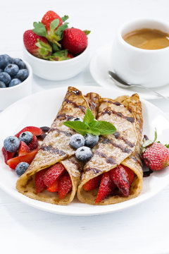 crepes with berries and chocolate sauce for breakfast, vertical