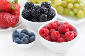 Fresh garden berries and grapes on a white wooden table