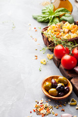 Fototapeta na wymiar Italian food background with vine tomatoes, basil, spaghetti, olives Ingredients on stone table Copy space