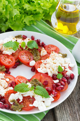 fresh salad with tomatoes, cottage cheese, pesto and pomegranate