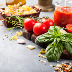 Italian food background with vine tomatoes, basil, spaghetti, olives Ingredients on stone table Copy space