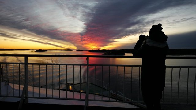 Cruise ship vacation woman taking photo with smart phone enjoying sunset on travel at sea. Girl using smartphone to take picture of ocean sunset