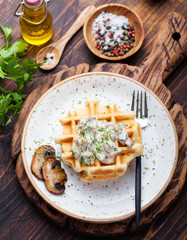 Savory waffles with corn and mushroom creamy sauce on a wooden background Top view
