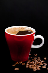 Red cup of coffee with coffee beans and dark background