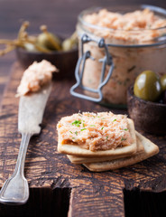 Smoked salmon and soft cheese spread, mousse, pate in a jar with crackers and capers on a wooden background