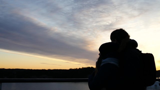 Silhouette of couple embracing on a ferry boat during sunset or sunrise.