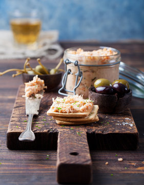 Smoked salmon and soft cheese spread, mousse, pate in a jar with crackers and capers on a wooden background