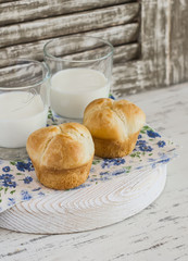 Homemade brioche bun and two glasses of milk on a light rustic wood background