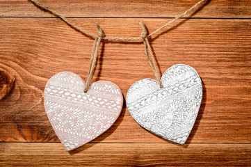 Wooden decorative hearts on brown wooden background.