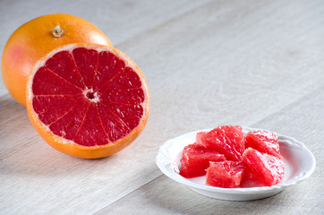 Slices of grapefruit on the plate and the grapefruit on the tabl