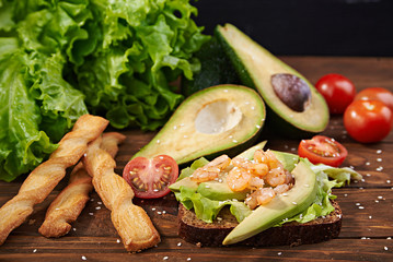 Rye bread sandwich with shrimp, avocado, tomatoes and breadsticks