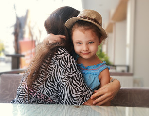 Happy kid girl embracing her beautiful mother outdoor summer bac