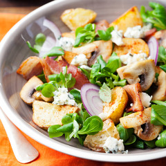 Potato salad with bacon, mushroom on orange napkin Wooden background