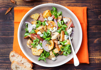 Potato salad with bacon, mushroom on orange napkin Wooden background Top view