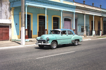 Kuba: Strassenszene mit US-amerikanischem Oldtimer vor farbenfrohem kubanischem Kolonialgebäude