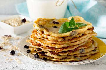 Milk and pancakes with honey and raisins, selective focus