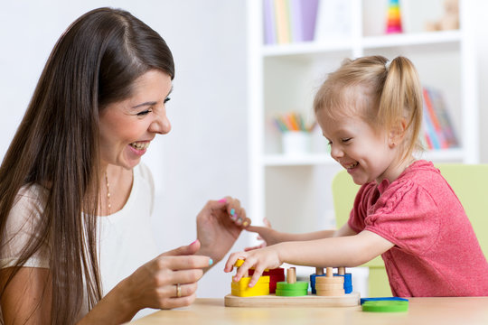 Cute woman and kid girl playing educational toys at home