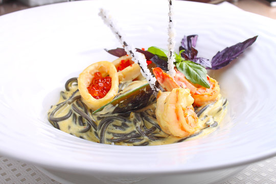 pasta with seafood (squid, mussels, shrimp, caviar) on a white background