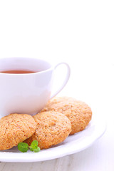 almond cookies in a white plate with a cup of tea