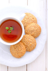 almond cookies in a white plate with a cup of tea
