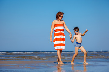 Mother and son having fun on beach during summer holiday vacation