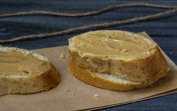 toast with peanut butter white bread on Kraft paper on gray blue painted wooden background