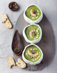 Broccoli, spinach cream soup with shrimp in a white bowls Top view